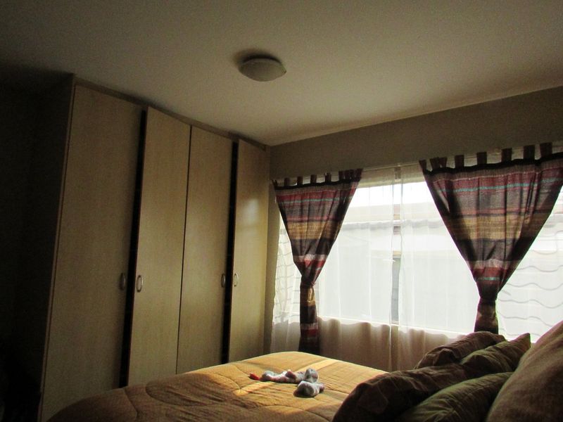 A bedroom featuring built-in cupboards and natural light from the window.