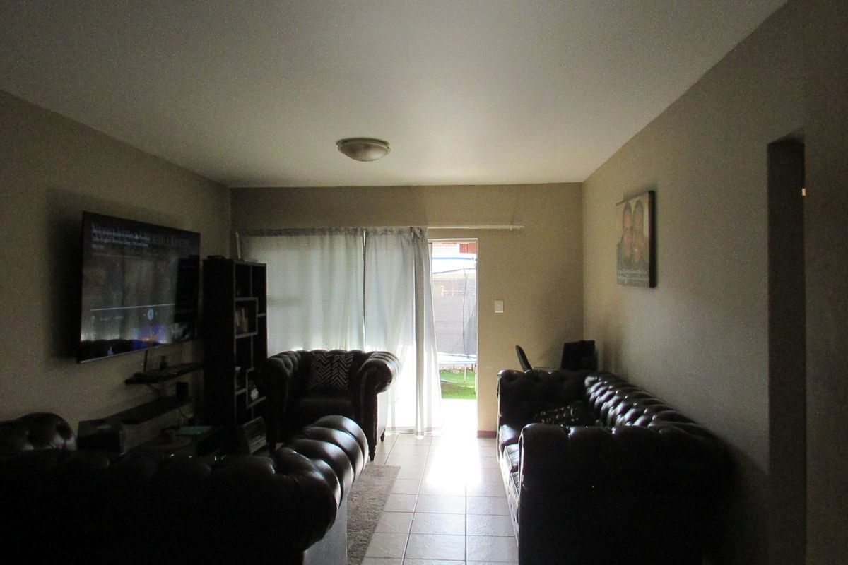 A living room featuring tiled flooring and a sliding glass door providing access to the outdoor area.