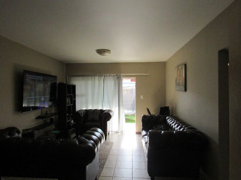 A living room featuring tiled flooring and a sliding glass door providing access to the outdoor area.
