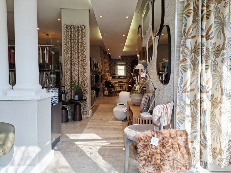 A well-lit open-plan commercial showroom space featuring stone flooring, recessed ceiling lighting, and decorative wall finishes, suitable for retail or design display.