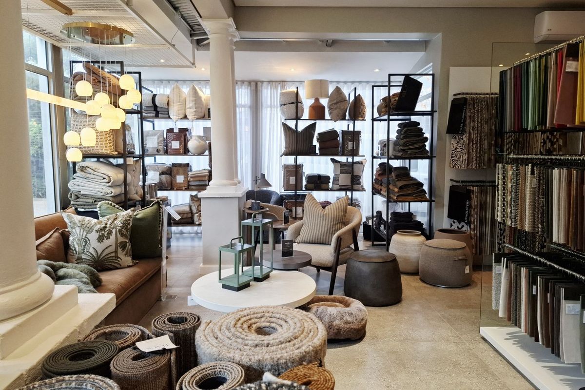 A well-lit commercial showroom space featuring tiled flooring, structural columns, and integrated display shelving, suitable for retail or design consultation purposes.