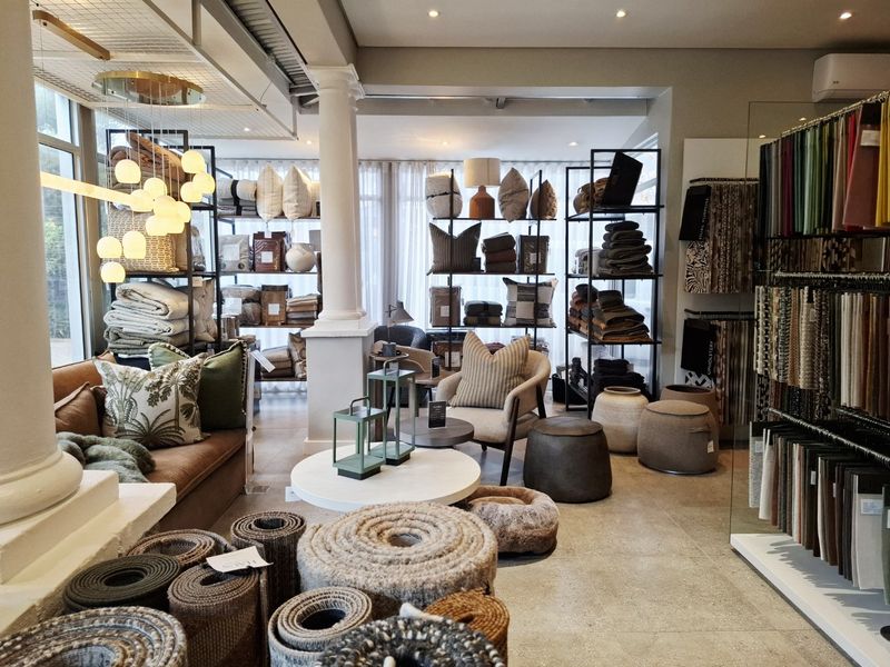 A well-lit commercial showroom space featuring tiled flooring, structural columns, and integrated display shelving, suitable for retail or design consultation purposes.