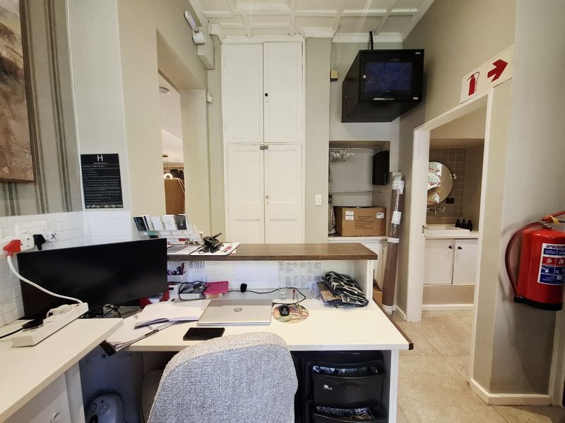 A functional commercial office space featuring built-in cabinetry, tiled flooring, and integrated fire safety equipment, providing a practical administrative work area.