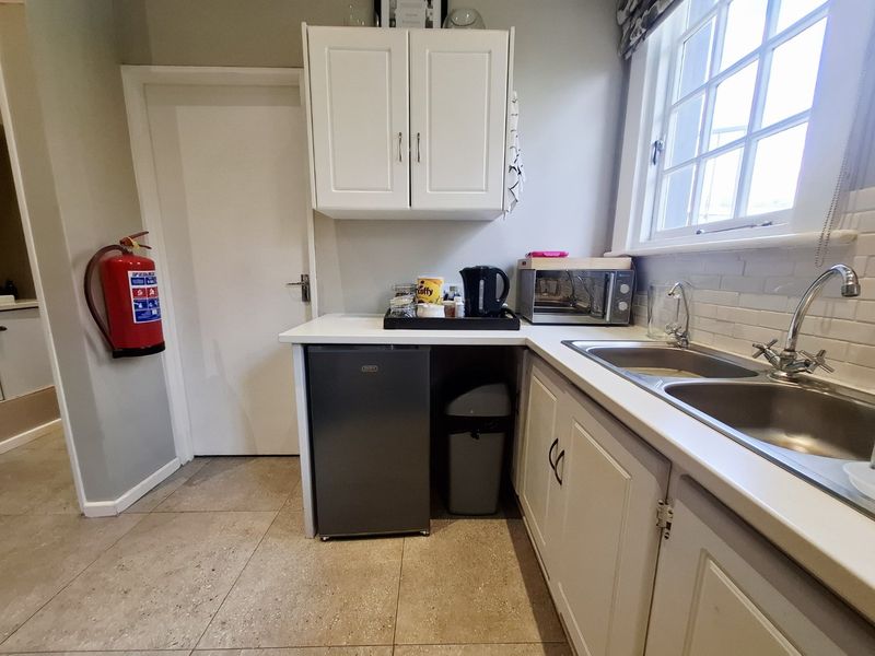 A functional scullery area featuring double stainless steel sinks, subway tile backsplash, and built-in cabinetry with ample counter space.