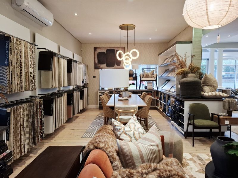 A well-appointed commercial showroom or office space featuring timber flooring, recessed lighting, wall-mounted air conditioning, and extensive built-in display shelving.