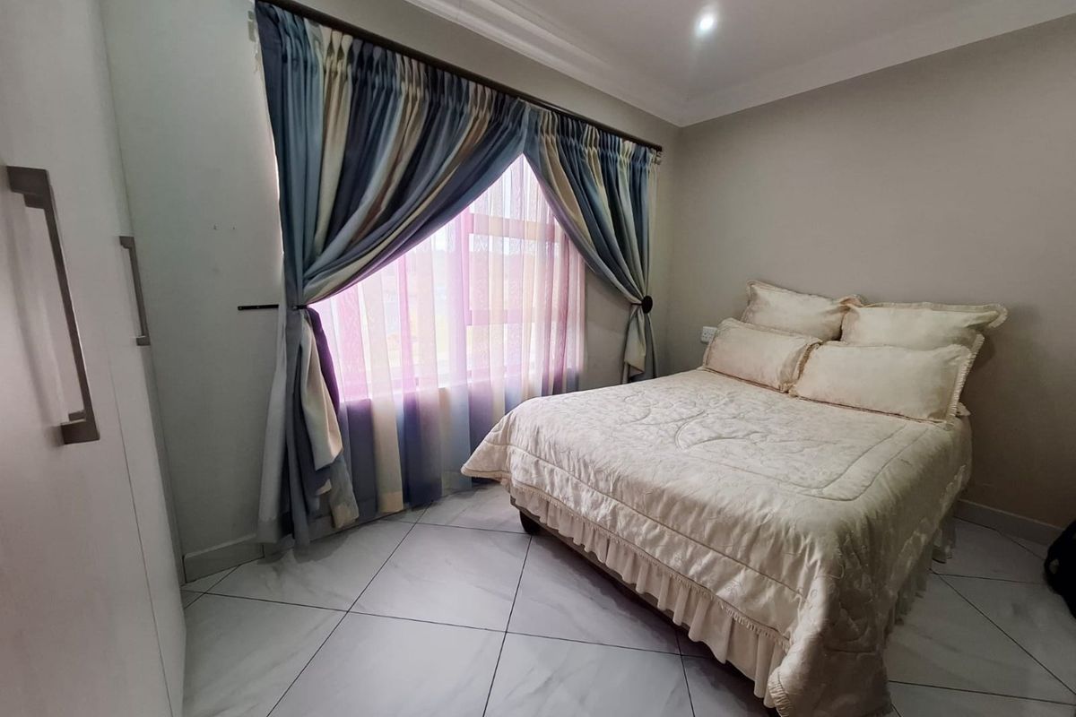 A well-maintained bedroom featuring tiled flooring, built-in wardrobe storage, and recessed ceiling lighting with decorative coving.