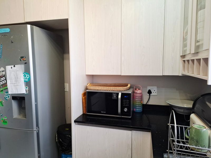 A functional kitchen area featuring light wood-grain cabinetry, black granite countertops, and a built-in microwave space.