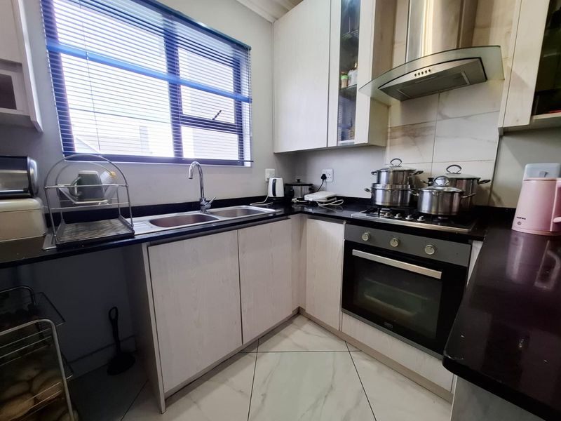A functional kitchen featuring light-toned cabinetry, dark granite countertops, a built-in oven with gas hob, and tiled flooring.