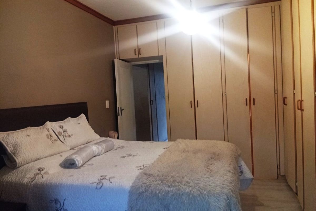 A bedroom featuring extensive built-in cupboards, crown molding, and laminate flooring, offering functional storage space.