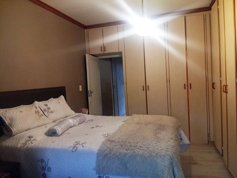 A bedroom featuring extensive built-in cupboards, crown molding, and laminate flooring, offering functional storage space.