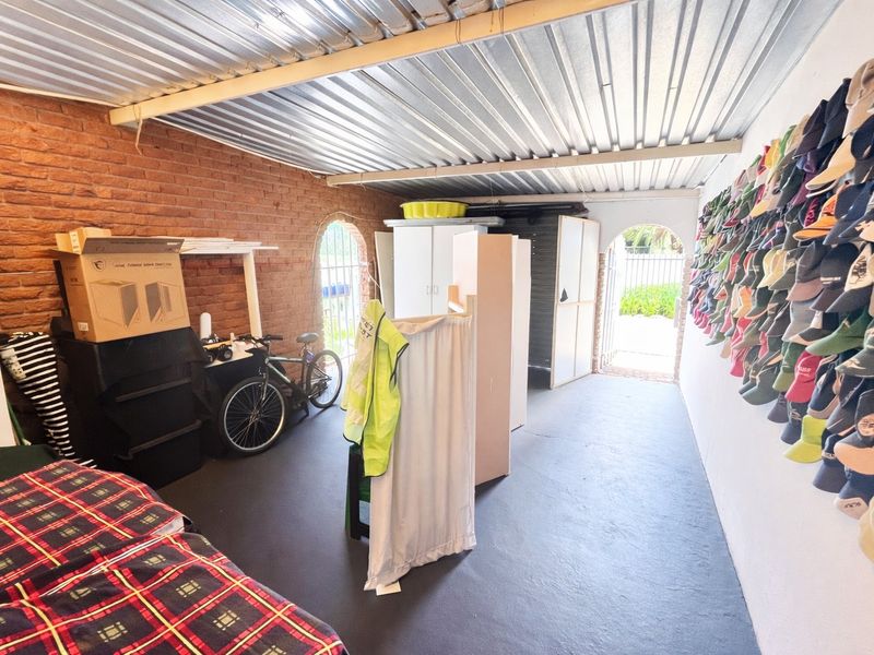 A functional garage space featuring exposed brick walls, a corrugated metal ceiling, and a painted concrete floor with direct access to the exterior.
