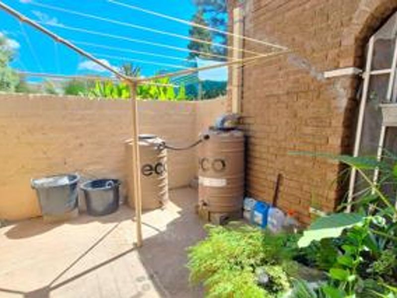 A functional rear courtyard area featuring brick walls, a rotary clothesline, and installed water storage tanks.