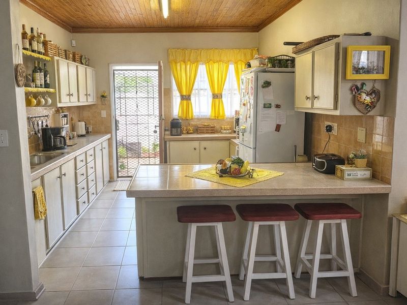 A functional kitchen featuring tiled countertops, ample built-in cabinetry, a double sink, and a distinctive timber ceiling with direct access to the exterior.