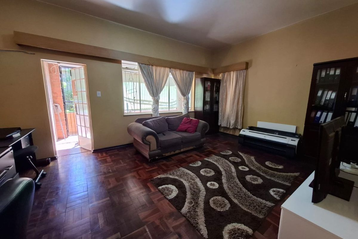 Spacious living room featuring classic parquet flooring and direct access to an outdoor area through a glass-paneled door.