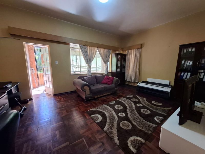 Spacious living room featuring classic parquet flooring and direct access to an outdoor area through a glass-paneled door.