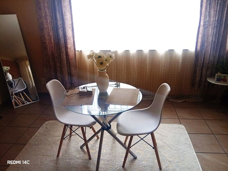 A dining area featuring tiled flooring and a large window with curtains, providing natural light to the space.