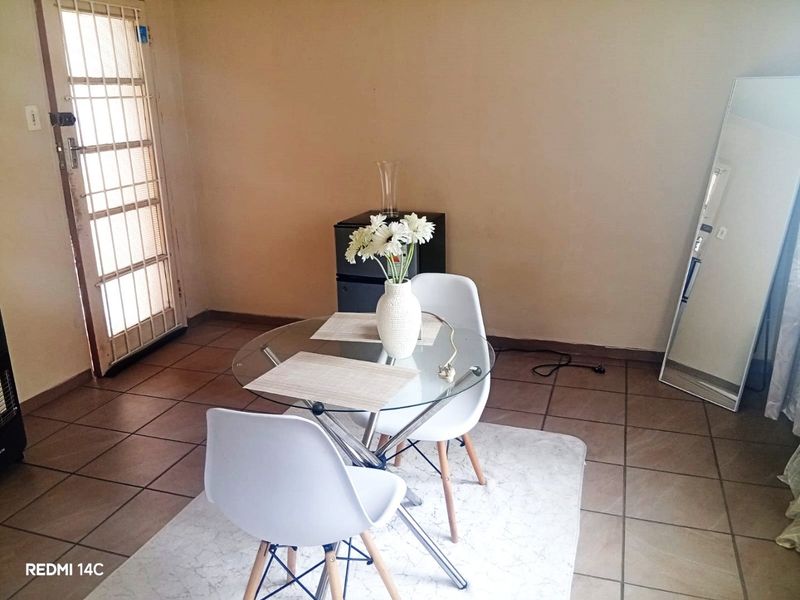A simple living area featuring tiled flooring and a security gate leading to the exterior.