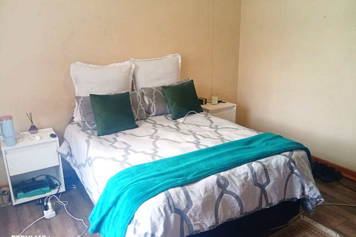A bedroom featuring laminate flooring and neutral wall finishes, currently showing signs of wear and requiring cosmetic updates.