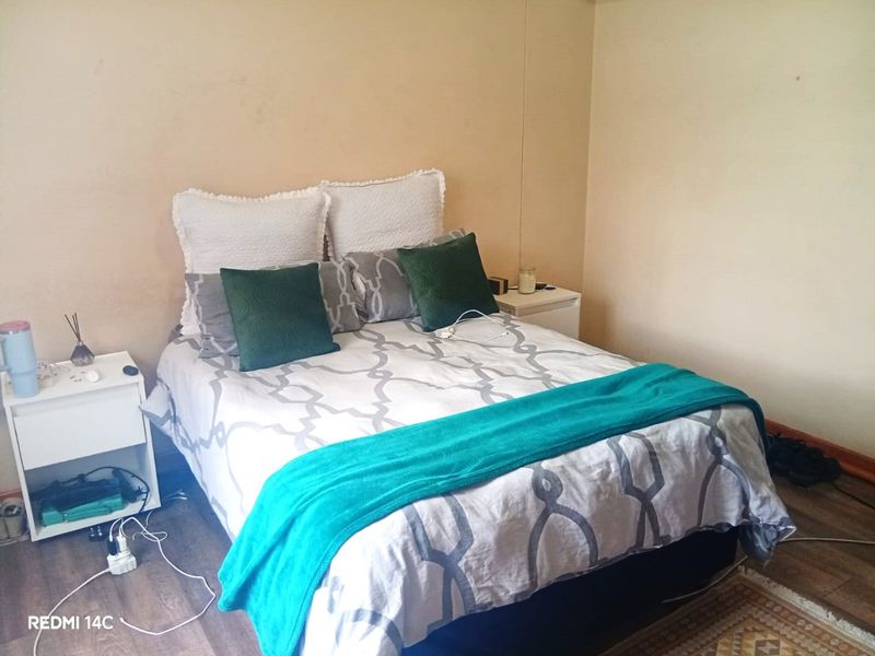 A bedroom featuring laminate flooring and neutral wall finishes, currently showing signs of wear and requiring cosmetic updates.