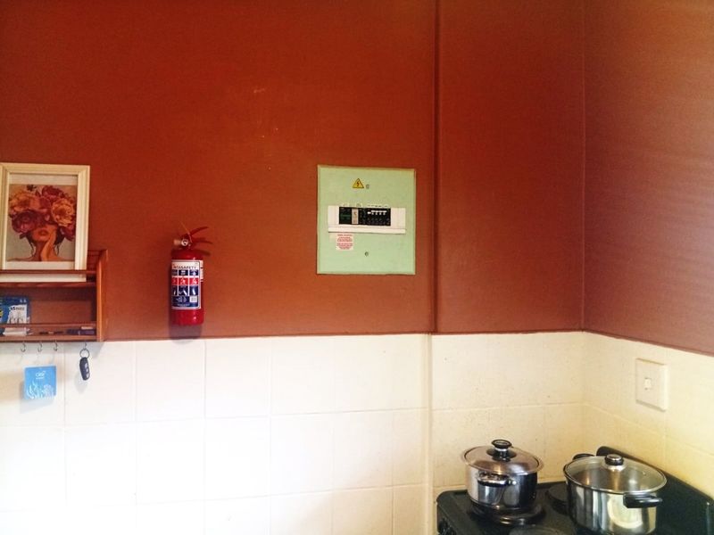 A kitchen area featuring a tiled splashback, a wall-mounted electrical distribution board, and a fire extinguisher.