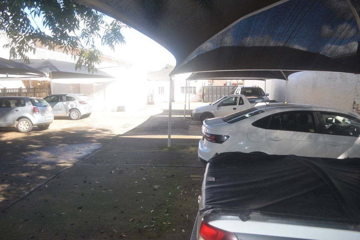 A paved outdoor parking area featuring multiple shade cloth carports and perimeter walling, providing functional covered vehicle storage for the commercial property.