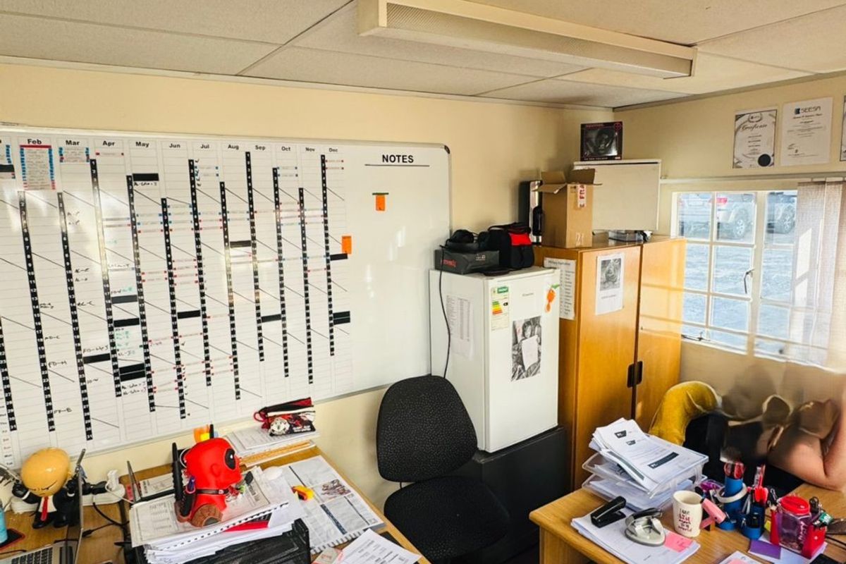 A functional commercial office space featuring a suspended ceiling, fluorescent lighting, and a multi-pane window, currently utilized as a workspace.