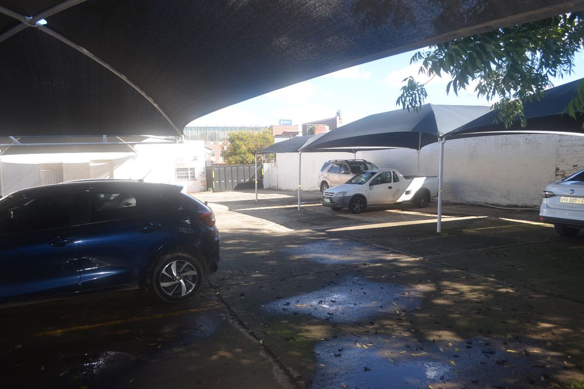 Commercial parking area featuring multiple shade cloth carports and concrete paving, providing functional outdoor vehicle storage space.