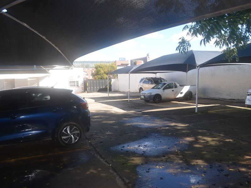 Commercial parking area featuring multiple shade cloth carports and concrete paving, providing functional outdoor vehicle storage space.
