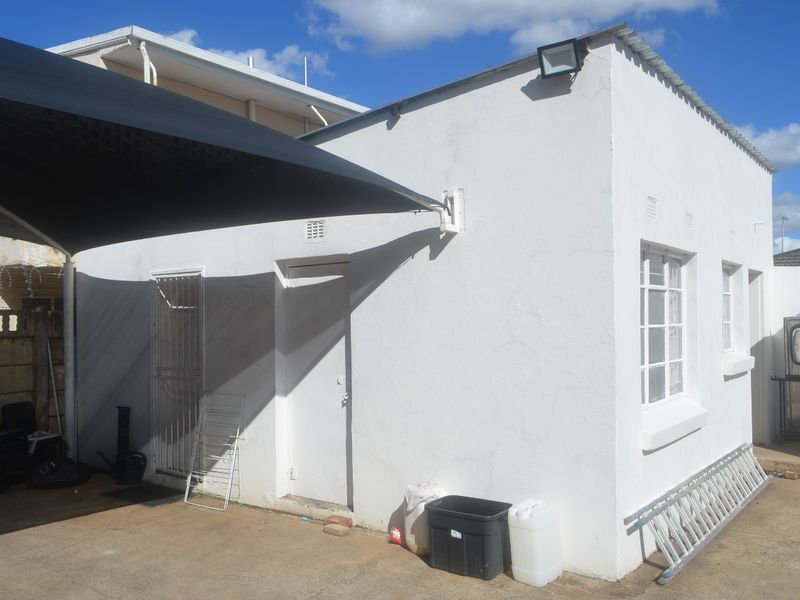 Rear exterior view of the commercial building featuring a shade sail, concrete paving, and security gate access.