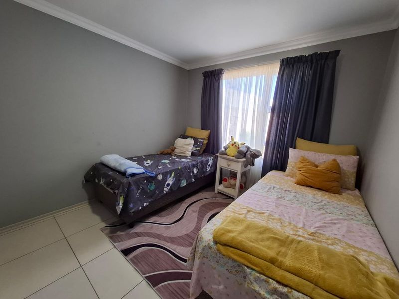 A functional bedroom featuring tiled flooring and decorative ceiling cornicing, providing a neutral base for personalization.