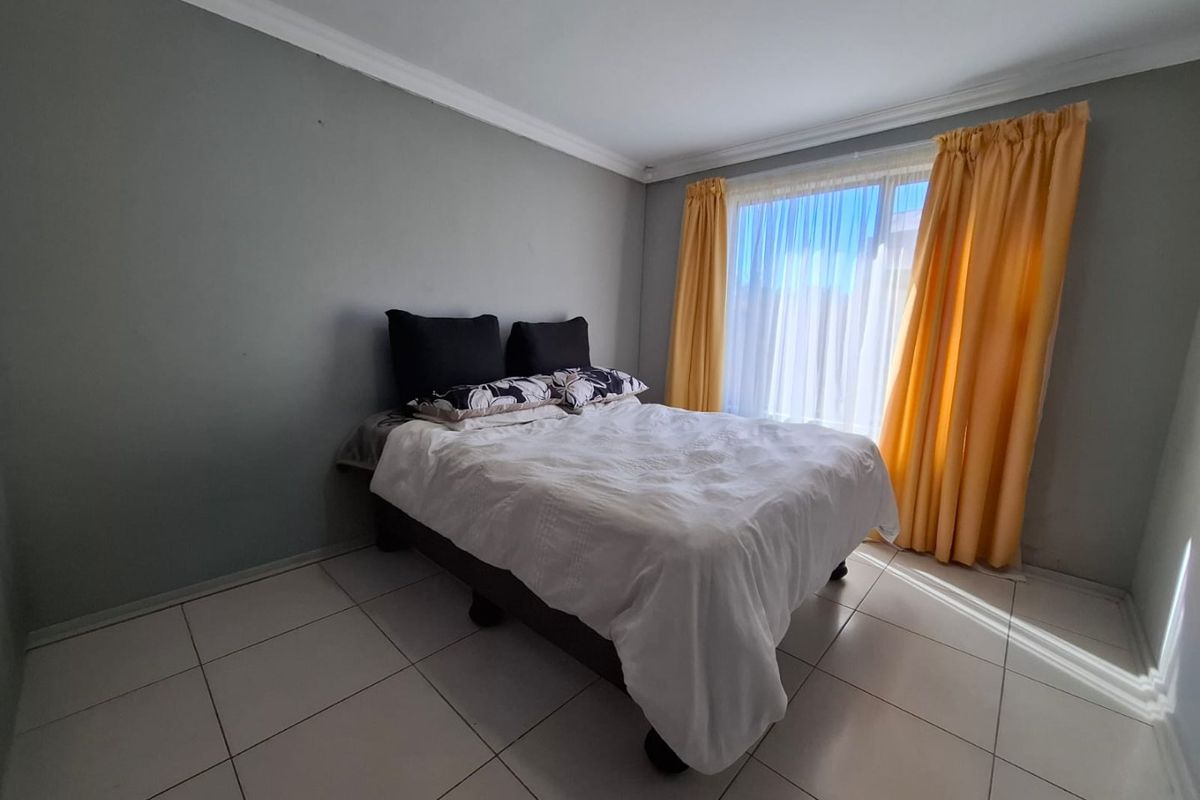 A bedroom featuring tiled flooring, neutral wall finishes, and a large window with natural light.
