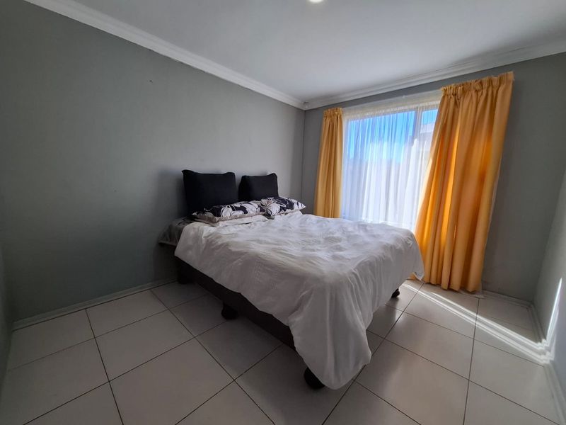 A bedroom featuring tiled flooring, neutral wall finishes, and a large window with natural light.