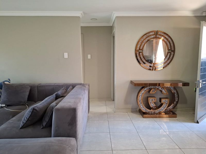 A well-maintained living area featuring neutral wall tones, tiled flooring, and decorative crown molding, providing a clean and bright atmosphere.