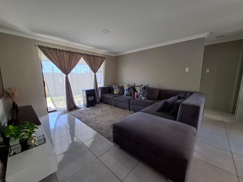 A well-maintained living room featuring large format floor tiles, recessed lighting, and a sliding glass door providing access to the outdoor area.