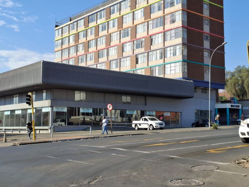 A multi-story commercial building featuring a prominent ground-floor showroom with large glass windows and a distinctive metal fascia, situated along a busy street.