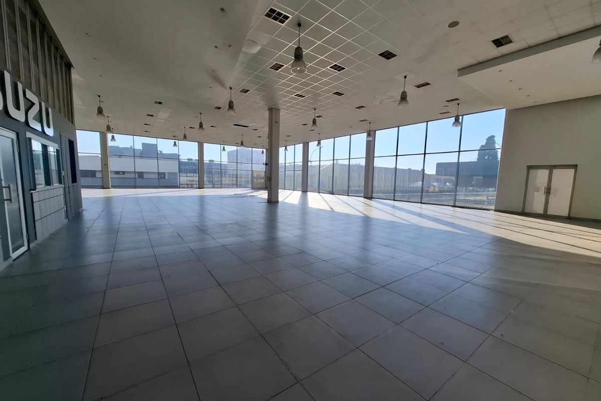 Spacious open-plan commercial showroom featuring large floor-to-ceiling windows, tiled flooring, and a suspended ceiling, offering excellent natural light and versatile layout potential.