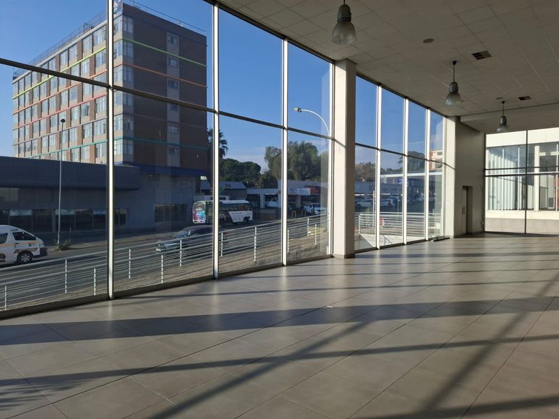 Spacious open-plan commercial area featuring extensive floor-to-ceiling glass windows, tiled flooring, and modern suspended ceiling lighting, offering excellent natural light and street visibility.