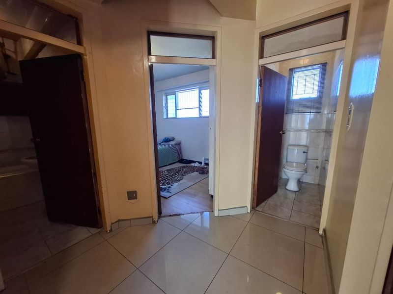 A central hallway featuring tiled flooring and access to multiple rooms, including a bathroom and bedroom, with neutral wall finishes.