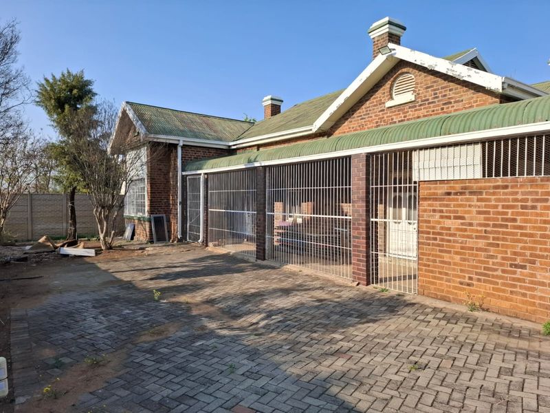 Rear exterior view of a brick commercial building featuring a paved courtyard, corrugated metal roofing, and secure metal grille enclosures.