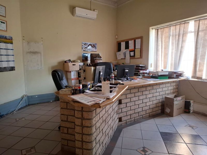 A commercial office space featuring a built-in brick reception counter, tiled flooring, and a wall-mounted air conditioning unit.