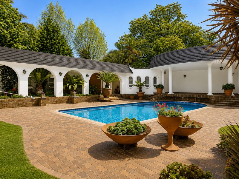 A beautifully maintained outdoor pool area featuring brick paving, an elegant arched colonnade, and a covered patio space perfect for relaxation and entertainment.