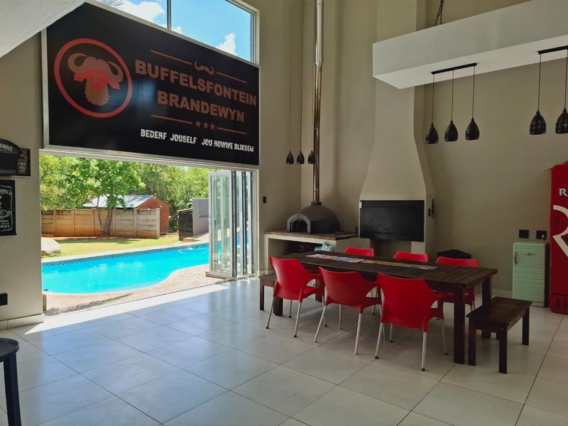 Spacious open-plan living area featuring a built-in fireplace, pizza oven, and large stacking doors opening directly onto the pool area.