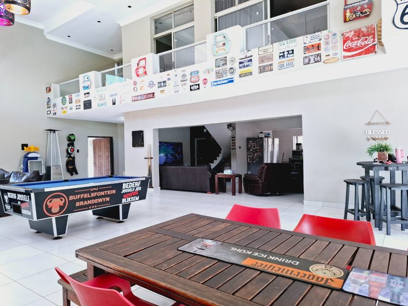 Spacious open-plan living area featuring high ceilings, a mezzanine level with glass balustrade, and tiled flooring throughout.