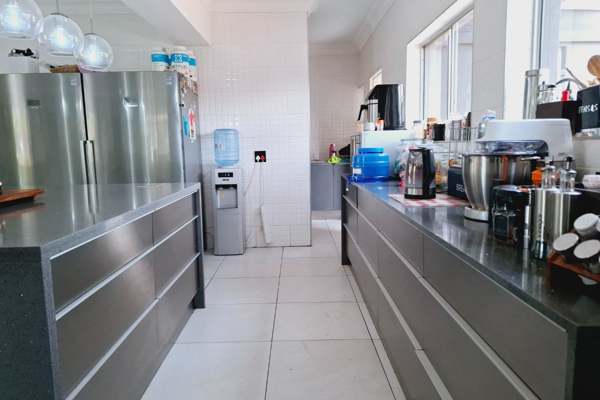 Modern galley-style kitchen featuring sleek stainless steel cabinetry, stone countertops, and clean tiled finishes, offering a functional and contemporary workspace.