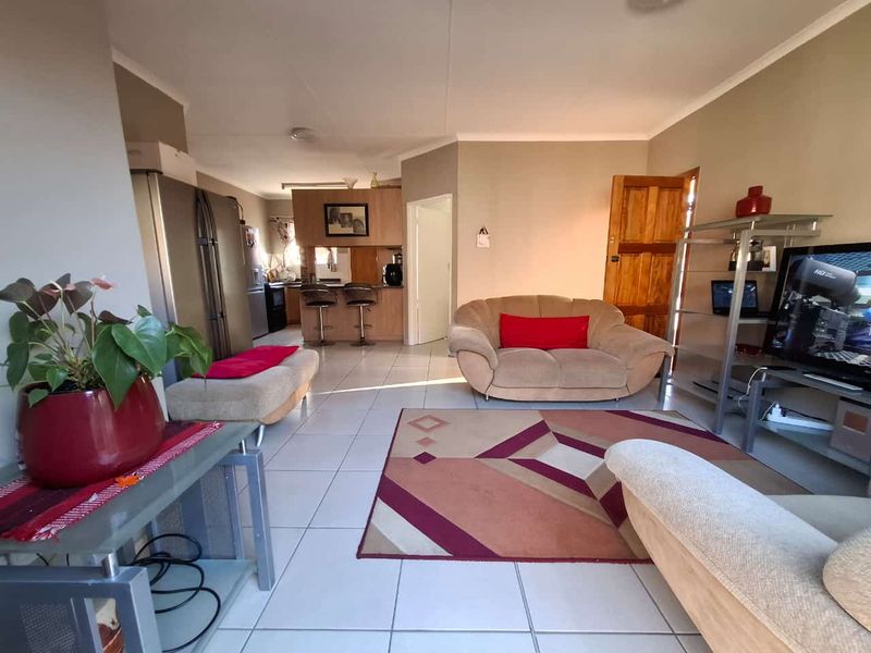 Open-plan living area featuring tiled flooring and a connected kitchen with a breakfast counter, providing a functional and versatile living space.