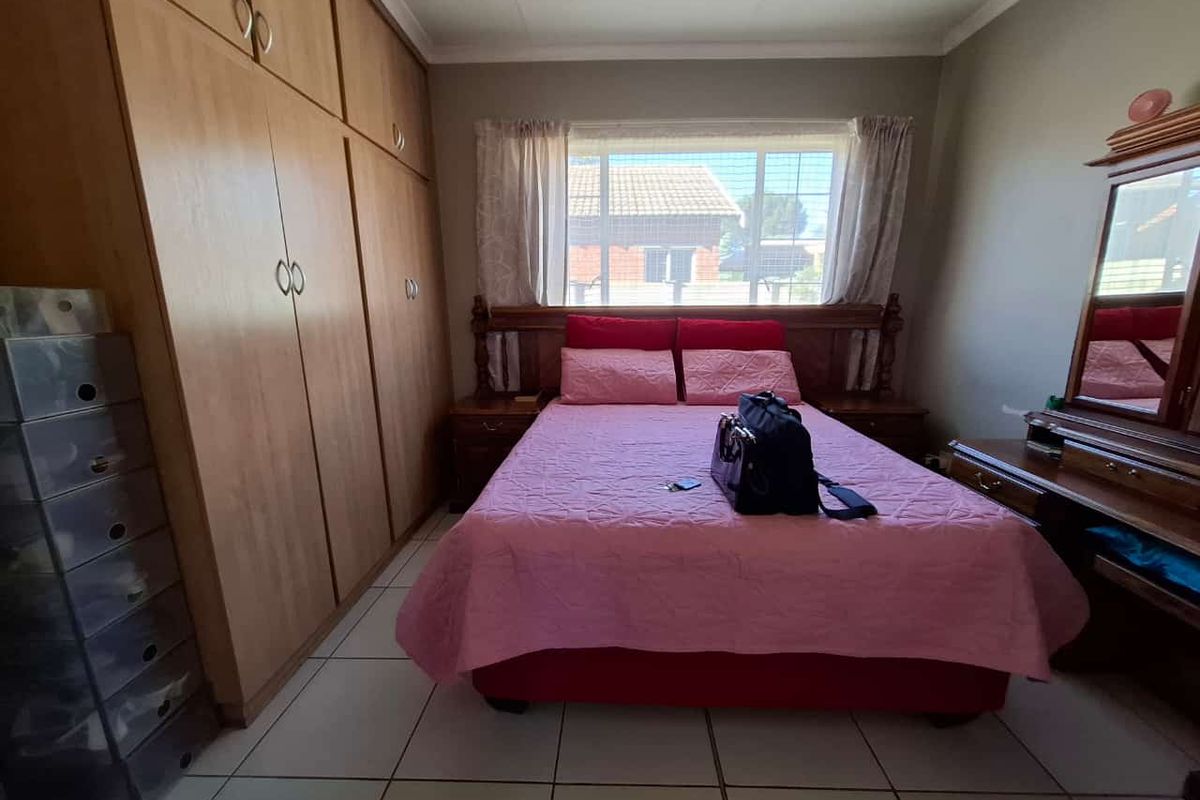 A functional bedroom featuring built-in wooden cupboards and tiled flooring, providing ample storage space and a neutral foundation for interior design updates.