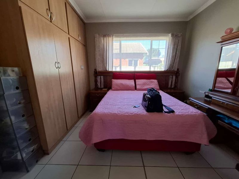 A functional bedroom featuring built-in wooden cupboards and tiled flooring, providing ample storage space and a neutral foundation for interior design updates.