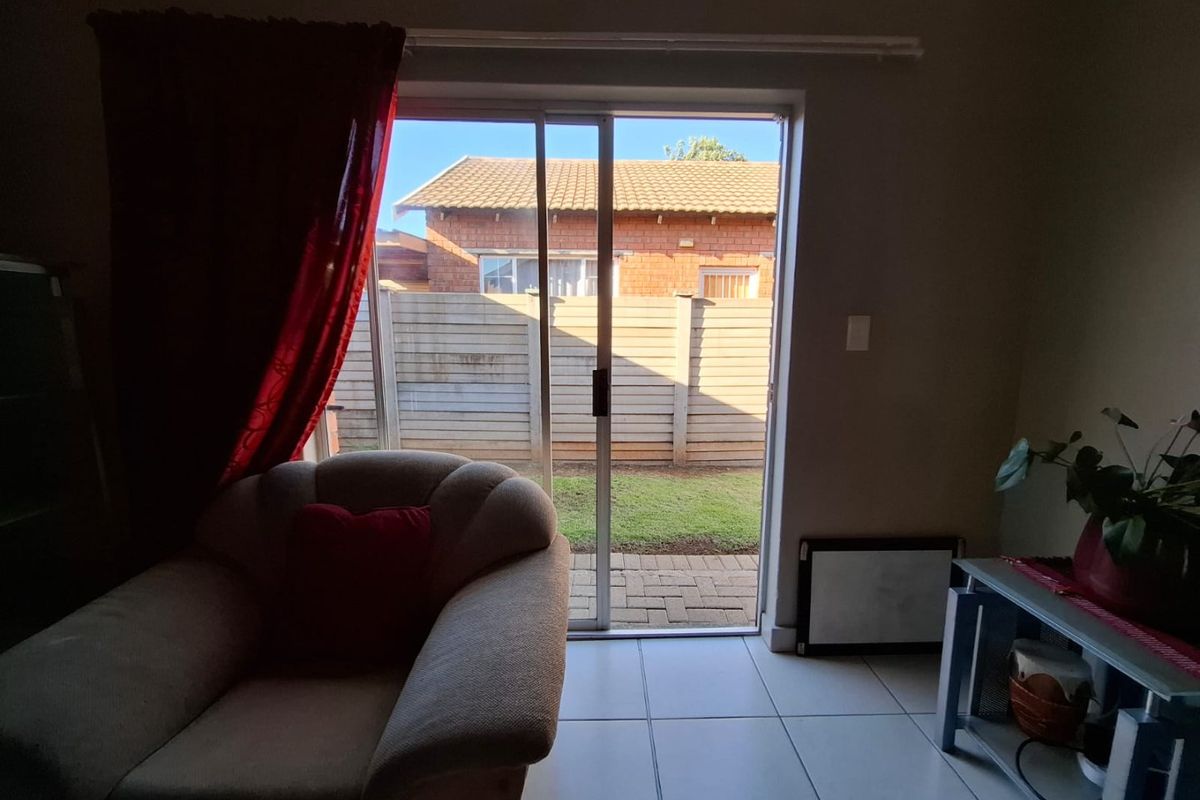 Living area featuring tiled flooring and a sliding glass door providing direct access to the rear garden and patio area.