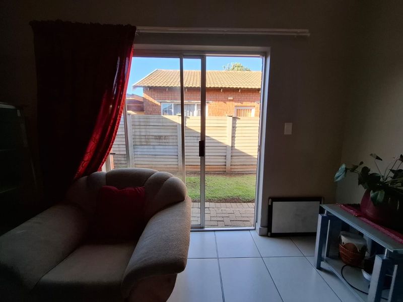 Living area featuring tiled flooring and a sliding glass door providing direct access to the rear garden and patio area.
