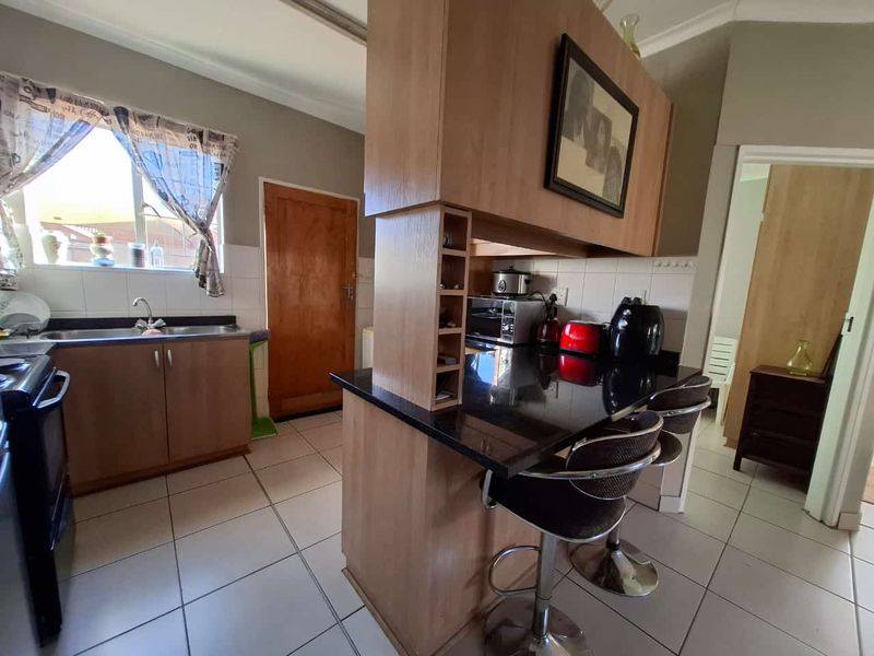 A functional kitchen featuring laminate cabinetry, black granite countertops, a breakfast bar, and tiled flooring, providing a practical layout for daily meal preparation.